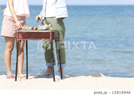 浜辺でバーベキューをするカップル 13819946