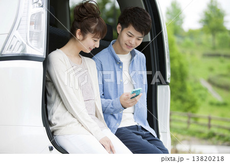 車に座ってスマーフォンを操作するカップル 13820218