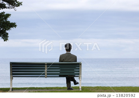 ベンチに座るビジネスマンの後ろ姿の写真素材