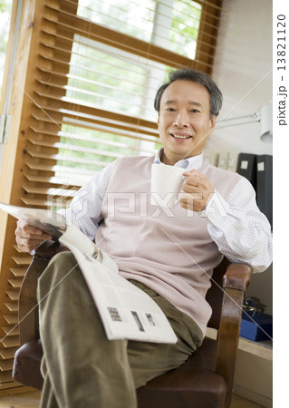 カップ片手に雑誌を読むシニア男性の写真素材 1311