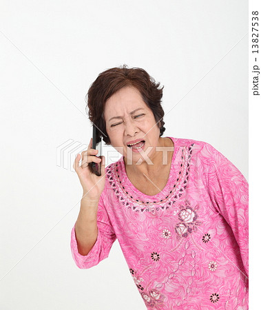 Senior elderly woman talking cellphone difficulty hearing  13827538