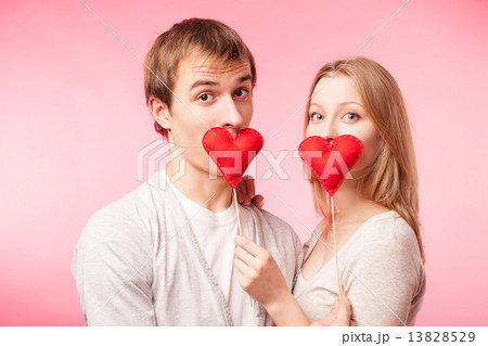 Couple hiding their lips behind little red hearts Couple hiding their lips behind little red hearts 13828529
