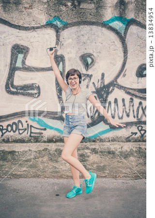 young hipster woman listening to music jumping 13834954