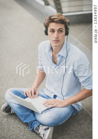 young model hansome blonde man with notebook and headphones 13834997