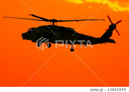 鮮やかな夕焼けを背景に飛行する海上自衛隊のSH-60Kシーホーク対潜哨戒ヘリコプター 13842959