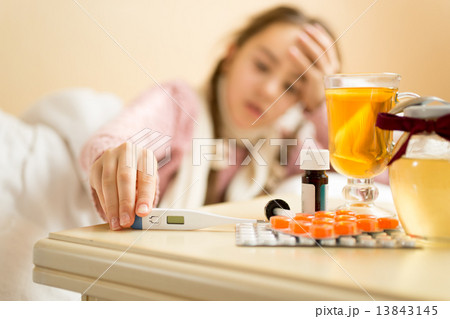 portrait of sick girl lying in bed and taking thermometer from t portrait of sick girl lying in bed and taking thermometer from t 13843145