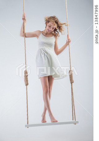 Young bare-footed girl on swing looking down. Young bare-footed girl on swing looking down. 13847996