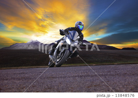 young man riding motorcycle in asphalt road curve with rural and 13848576