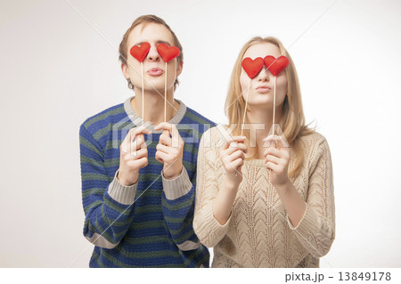 Couple hiding their eyes behind little red hearts Couple hiding their eyes behind little red hearts 13849178