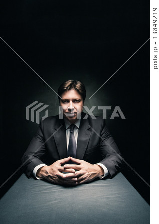 Man wearing suit in dark room illuminated by light 13849219