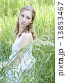 Photo of young blonde woman sitting in the green grass and looki 13853467