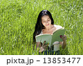Photo of young attractive brunette woman sitting on grass and re 13853477