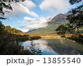 Lake, mirror lake with white puffy cloud on sunny day landscape framed by foliage 13855540
