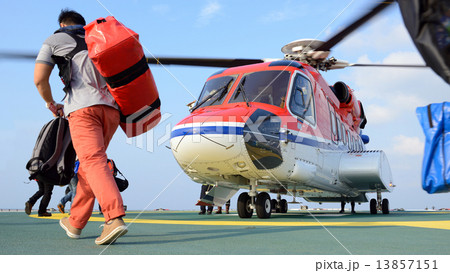 passenger carry his baggage to embark helicopter at oil rig plat 13857151