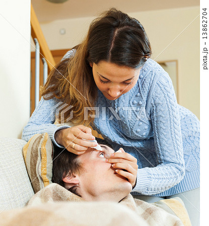 woman dripping collyrium to man 13862704