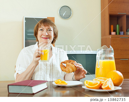 mature woman having breakfast with book mature woman having breakfast with book 13862735