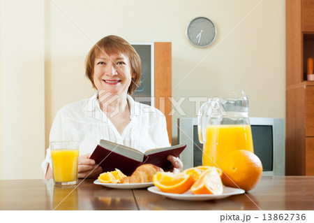 mature woman having breakfast with book mature woman having breakfast with book 13862736