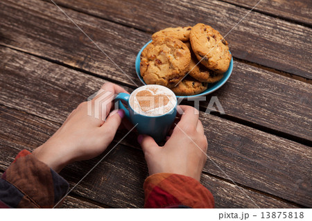 Female hands holding cup of coffee and cookies on wooden table. Female hands holding cup of coffee and cookies on wooden table. 13875818