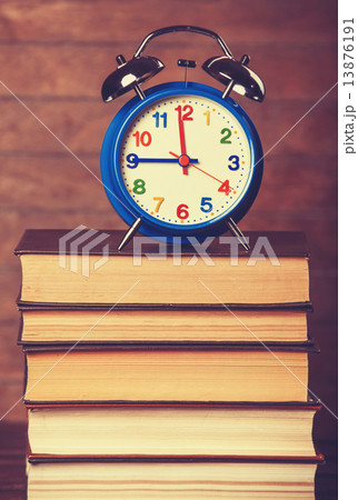 Alarm clock and books on wooden table. Alarm clock and books on wooden table. 13876191