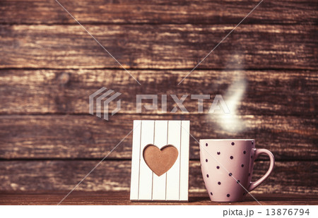 Frame with heart shape and cup of coffee on wooden background. Frame with heart shape and cup of coffee on wooden background. 13876794