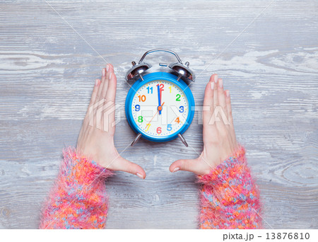 Female hands holding clock on a table. 13876810