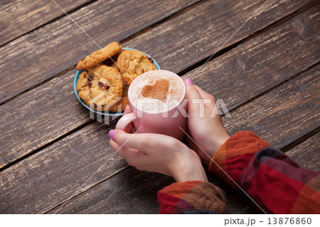 Female hands holding cup of coffee and cookies on wooden table. Female hands holding cup of coffee and cookies on wooden table. 13876860