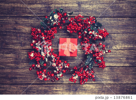 Holly christmas wreath and gift box on wooden table. Holly christmas wreath and gift box on wooden table. 13876861