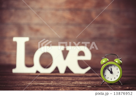 Clock with word love on wooden table. 13876952