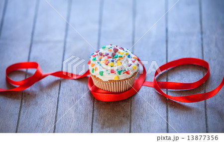 Cupcake and bow on wooden table. 13877356