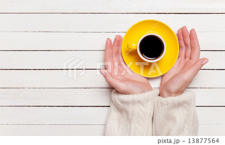 Female hands holding cup of coffee on wooden table. 13877564