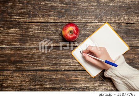 Female hand writing something in to notebook near apple 13877765