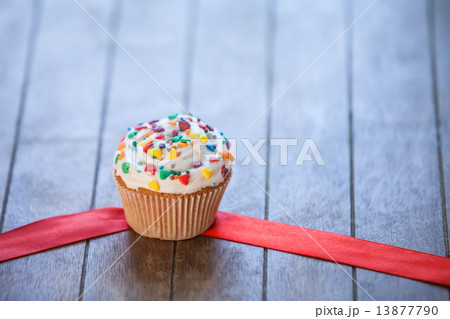 Cupcake and bow on wooden table. Cupcake and bow on wooden table. 13877790