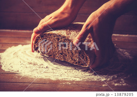 Baker's hands with a bread. Photo with high contrast 13879205
