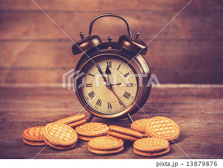 Retro alarm clock with cookie on a table Retro alarm clock with cookie on a table 13879876