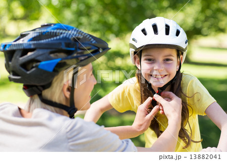 Mother attaching her daughters cycling helmet Mother attaching her daughters cycling helmet 13882041