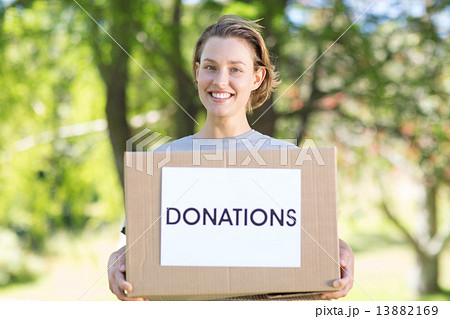 Happy volunteer in the park holding box 13882169