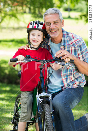 Happy little boy on his bike with his father Happy little boy on his bike with his father 13882572