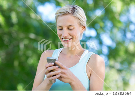 Pretty blonde using smartphone 13882664