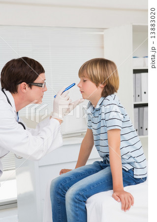 Doctor examines little boy with a light 13883020