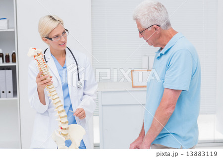 Orthopedic doctor explaining anatomical spine to senior man Orthopedic doctor explaining anatomical spine to senior man 13883119
