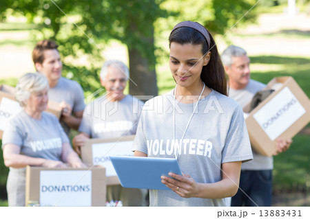 Smiling volunteer brunette using tablet pc Smiling volunteer brunette using tablet pc 13883431