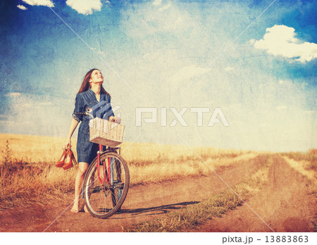 Brunette girl with bycicle on countryside road. Brunette girl with bycicle on countryside road. 13883863