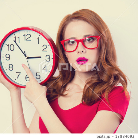 Surprised redhead girl with huge alarm clock on light background 13884092