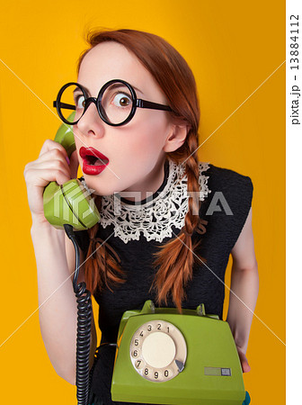 Redhead girl with green phone on yellow background. 13884112