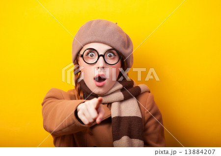 Redhead girl in coat and scarf on yellow background. 13884207