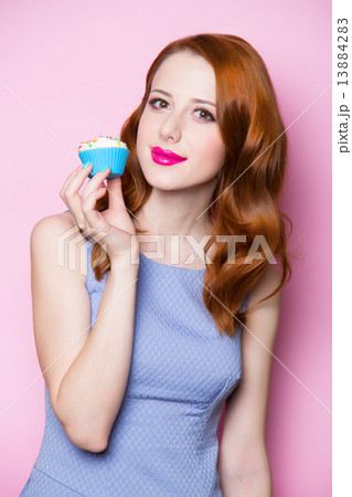 Redhead girl with cupcake in pink background. 13884283
