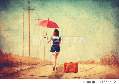 Beautiful brunette girl with suitcase and umbrella on the countr 13884412