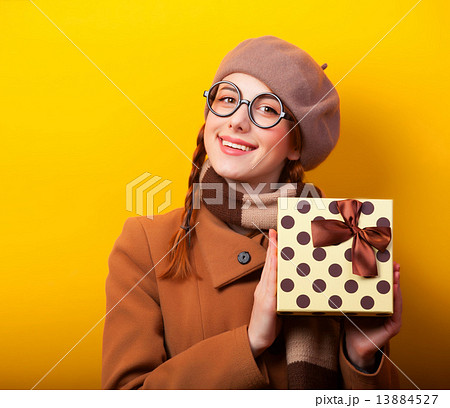 Redhead girl with gift box on yellow background. 13884527