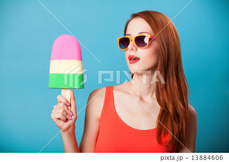 Redhead girl with toy ice cream on blue background. 13884606