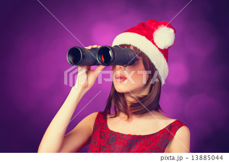Brunette girl with binocular and hat on violet background. 13885044